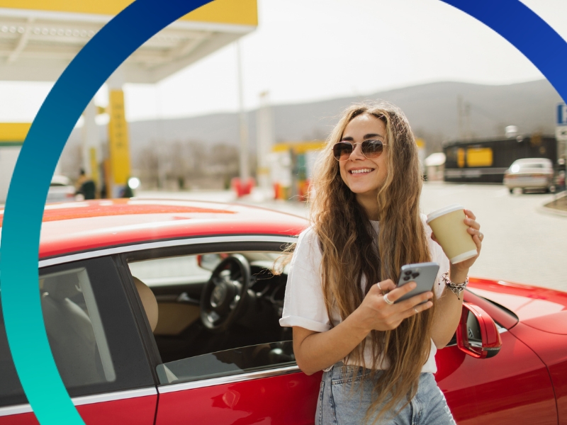 Young woman standing by a car taking a break from a road trip.